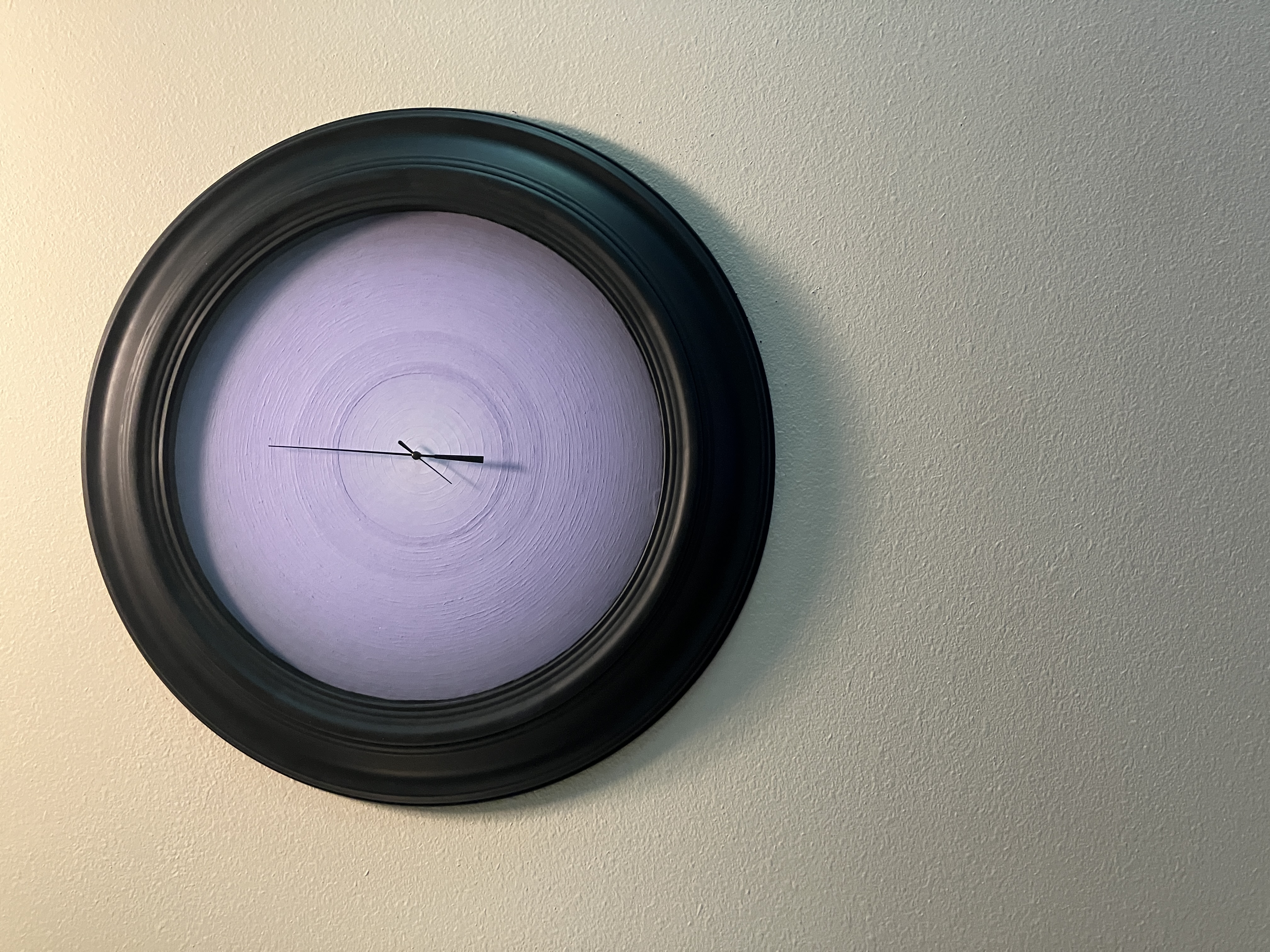 circular multimedia painting with 50 shades of purple getting lighter as you go inward as the face of a broken clock, set to 12:40, clock hands and frame are a matte black